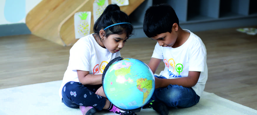 Two children exploring a globe at a pre-primary school in Yelahanka...